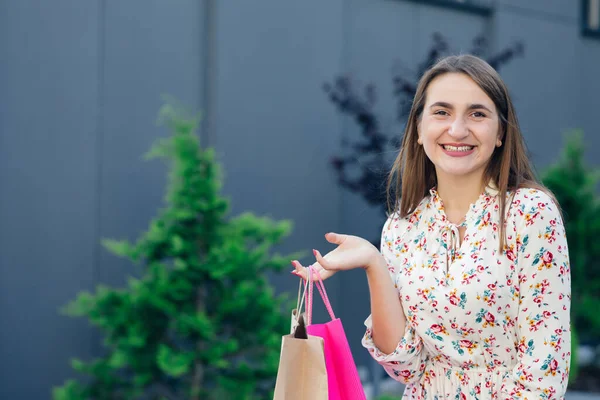 Νεαρή γυναίκα ψωνίζει. Ψώνια νεαρή γυναίκα χαμογελά στο εμπορικό κέντρο. Γυναίκα με τσάντες για ψώνια. — Φωτογραφία Αρχείου