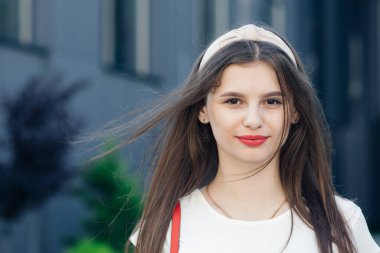 Güzel bir kadın. Genç, gülümseyen bir kadın şehirde eğleniyor. Kırmızı ruj. Çekici kırmızı dudaklı, parlak makyajlı, seksi gülümseyen beyaz kadın modelinin portresi..