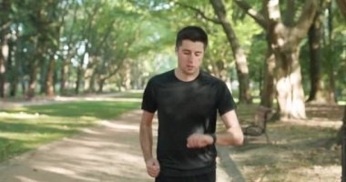 Parktaki boş yolda koşan sporcu dışarıda antrenman yaparken kablosuz kulaklıklar kullanarak internetten akıllı saat uyarısını kontrol ediyor. Sağlıklı aktif yaşam tarzı. Uzaklık uygulaması