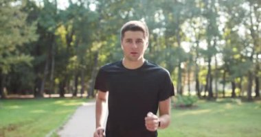 Şehir parkında koşan bir erkek. Kentsel iş adamı dışarıda taze doğanın tadını çıkarıyor. Sağlıklı aktif yaşam tarzı. Yaz güneşli bir sabah. Uzaklık spor uygulaması.