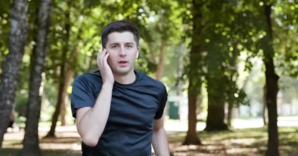 Erwachsener Mann läuft im Freien mit drahtlosen Kopfhörern Musik hören mit Smartwatch genießen gesund. Männlicher Läufer trainiert Cardio-Training im Stadtpark — Stockvideo