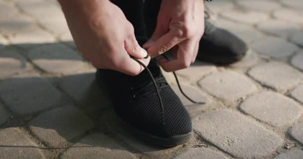 スポーツスニーカーで靴ひもを結ぶ男性の手はワークアウトを実行. — ストック動画