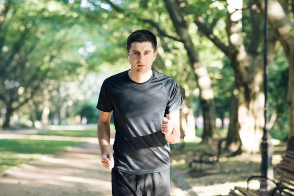 Un joven en ropa deportiva corriendo por el parque por la mañana. Estilo de vida activo. Cuidado de la salud y deportes. Hombre deportivo corriendo — Foto de Stock