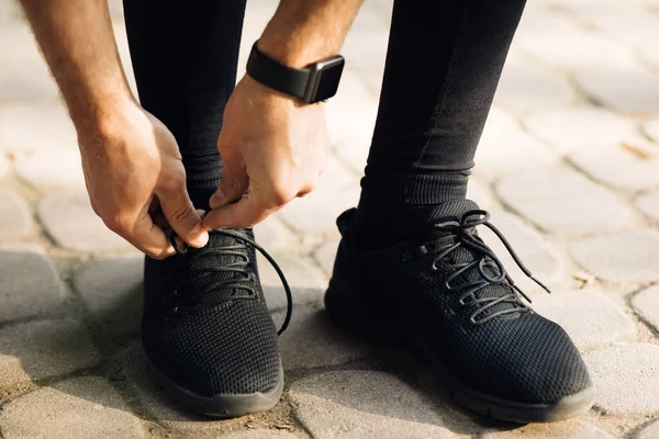 Manos masculinas atando cordones en zapatillas deportivas ejecutar entrenamiento. — Foto de Stock