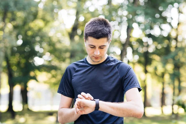 Hombre caucásico en uniforme deportivo usando smartwatch para medir la velocidad, la distancia, la remolacha del corazón que se preocupa por la salud física del cuerpo. Tecnología futurista. Prepárate. — Foto de Stock