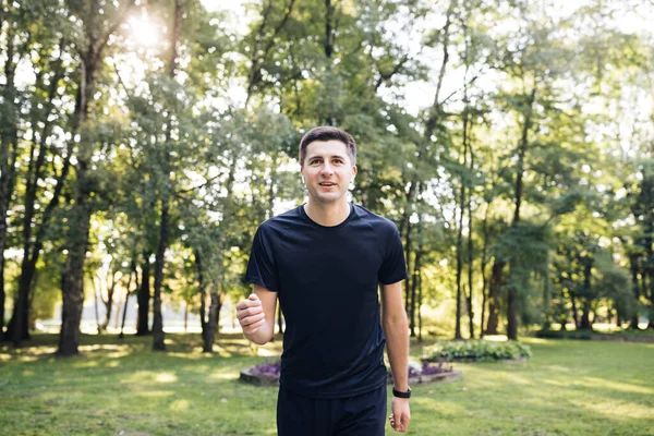 Spor giyim giymiş yetişkin bir adam sabahın erken saatlerinde parkta koşuyor. Spor insanları. Sporcu. Çalışan aktivite Sağlıklı yaşam tarzı — Stok fotoğraf