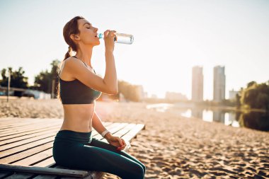 Nehir kıyısında su içen sporcu kadın