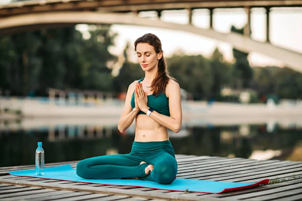 Sportswoman meditating on wooden platform