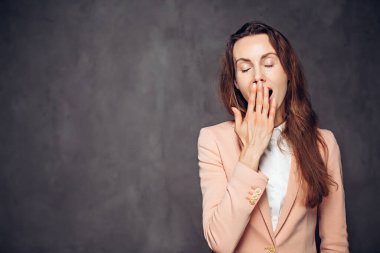 Siyah arka planda esneyen yetişkin beyaz kadın.