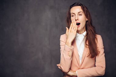 Siyah arka planda esneyen yetişkin beyaz kadın.