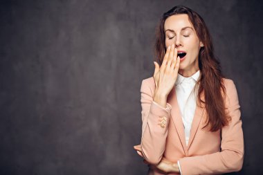 Siyah arka planda esneyen yetişkin beyaz kadın.