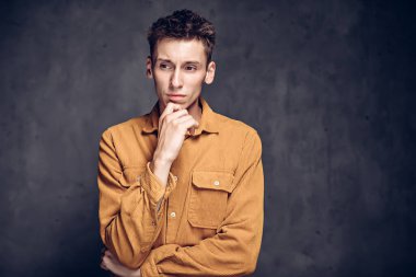 Esmer arka planda düşünceli beyaz bir adam.