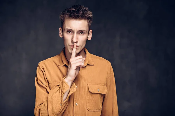 Kafkasyalı adam karanlık arka planda sessizlik işareti gösterdi