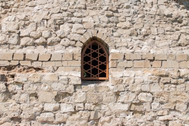 Taştan bir duvar ile barlar ile a küçük pencere. Eski taş duvar.