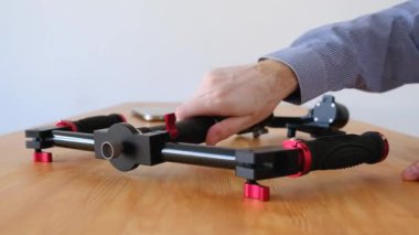 Mavi gömlekli erkek el ahşap masanın üzerinde yatan bir üç akslı teçhizat denetler. Kimliği belirsiz değerlendirme sadece sabitleyici Kamera için satın