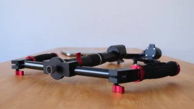 Yakın çekim - video çekim için üç eksenli teçhizat bulanık bir dizüstü bilgisayar arka planı masada yatıyor. Video ve fotoğraf için profesyonel donatım kavramı