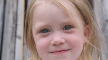 Büyük mavi gözlü gülen komik küçük sarışın kız portresi