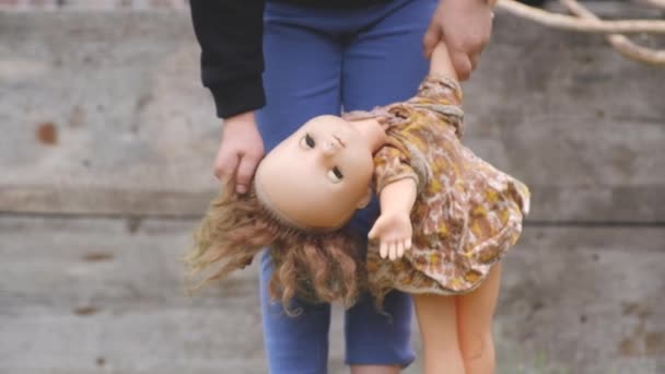 Små barn håller en gammal trasig docka i handen och i håret — Stockvideo