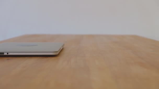 Portátil de plata se encuentra en una mesa de madera en la habitación vacía — Vídeo de stock