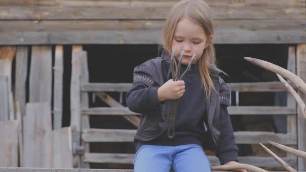 Kleines lustiges schönes Bauernmädchen schaut auf die alte Schmiedeharke — Stockvideo