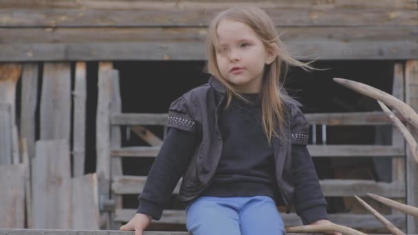 Beautiful stylish little village girl sitting on a wooden construction — Stock Video