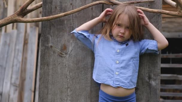 Az elegáns ruhákat, a háttérben egy fa képernyő pózol a kis aranyos lány — Stock videók