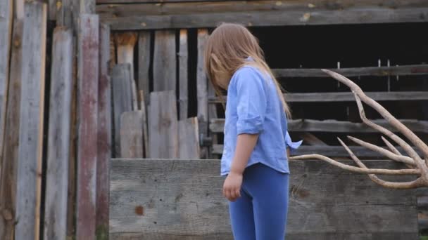 Menina em roupas azuis espreita atrás de uma tela de madeira — Vídeo de Stock