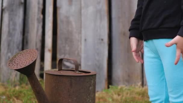 Petit enfant non identifié se tient près d'un vieil arrosoir rouillé — Video