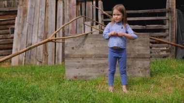 Mavi kıyafetlerle güzel küçük kız çıplak ayakla avluda ayakta