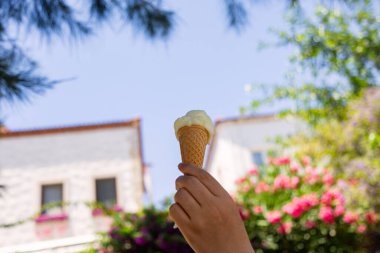 Ice cream cone in the hand of a woman on a background of flowers