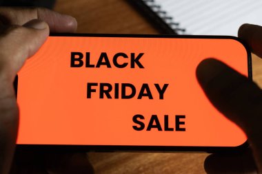 Mobil ekranda Kara Cuma indirimini gösteren bir metin tutan adam