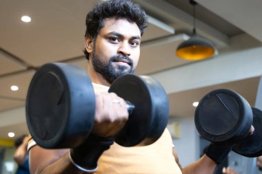 Genç bir adamın portresi. Spor salonunda egzersiz yapan genç bir adam. Artı boyut 