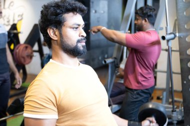 Genç bir adamın portresi. Spor salonunda egzersiz yapan genç bir adam. Artı boyut 