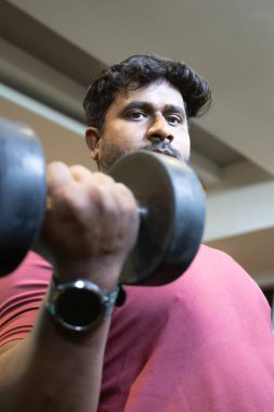 Genç bir adamın portresi. Spor salonunda egzersiz yapan genç bir adam. Artı boyut 