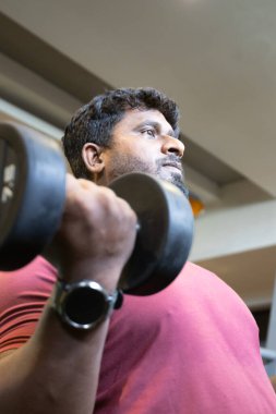 Genç bir adamın portresi. Spor salonunda egzersiz yapan genç bir adam. Artı boyut 