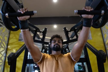 Genç bir adamın portresi. Spor salonunda egzersiz yapan genç bir adam. Artı boyut 