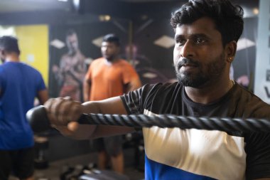 Genç Hintli arkadaşlar antrenmandan sonra sakinleşir. Biri spor salonunda diğerine çıplak ayakla masaj yapıyor.