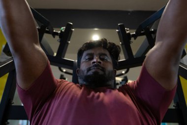 Genç bir adamın portresi. Spor salonunda egzersiz yapan genç bir adam. Artı boyut 