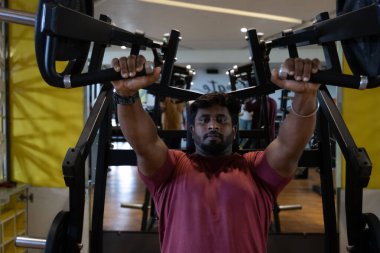 Genç bir adamın portresi. Spor salonunda egzersiz yapan genç bir adam. Artı boyut 