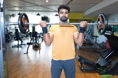 Genç bir adamın portresi. Spor salonunda egzersiz yapan genç bir adam. Artı boyut 