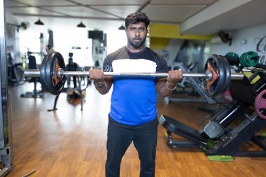 Genç bir adamın portresi. Spor salonunda egzersiz yapan genç bir adam. Artı boyut 