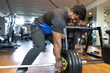 Spor salonunda ağırlık kaldırma. Genç bir adamın portresi. Genç 
