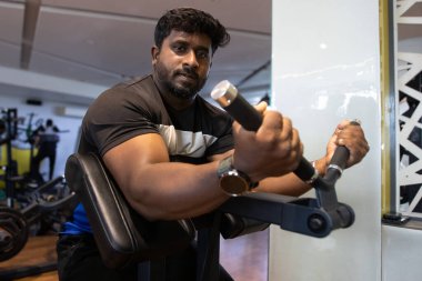 Genç bir adamın portresi. Spor salonunda egzersiz yapan genç bir adam. Artı boyut 