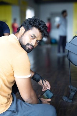 Gençler spor salonunda akıllı telefon kullanıyor. Mobil bağımlı