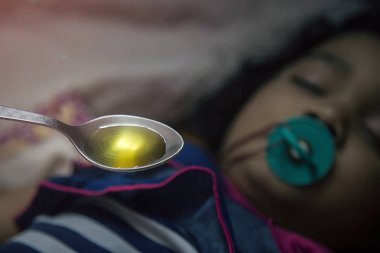 Tıp hapları ağzına emzik ile Asyalı çocuk üzerinde tutan el.