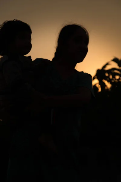 赤ちゃんの娘が遊んでいる若い母親のシルエット — ストック写真
