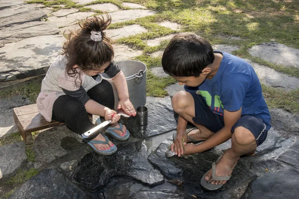 Çocuklar Shimla, Himachal Pradesh, Hindistan 'da açık alanda mutfak aletlerini temizliyor..