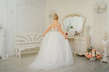 Zarif bir düğün saç stili olan güzel bir gelinin aynanın önünde nazikçe portresi.