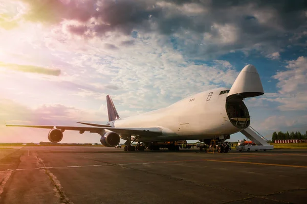 Unloading wide body transport cargo airplane in the morning sun