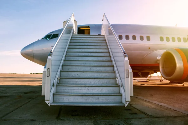 Passenger airplane with a boarding steps in the morning sun